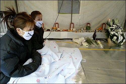 28일 오후 서울 성북구 미아리 집창촌 화재참사가 발생한 업소 부근에 설치된 분향소에서 동료들이 마스크를 쓴 채 앉아 있다. 